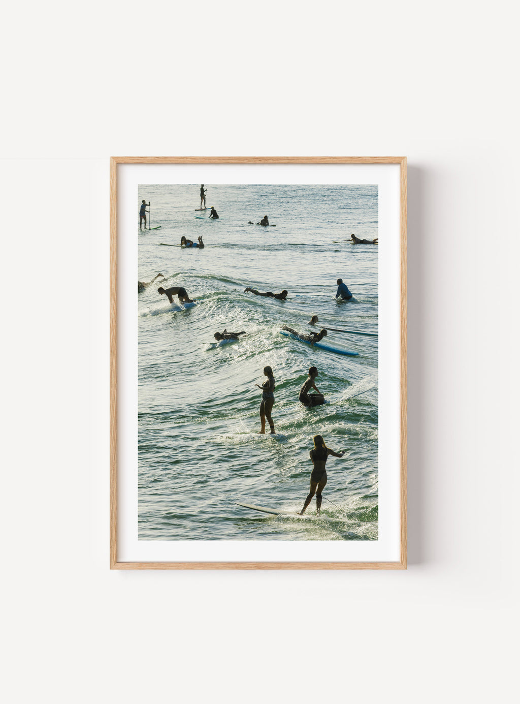 Surfers riding and paddling through layered waves in afternoon light at Yamba, Australia, mocked up in frame