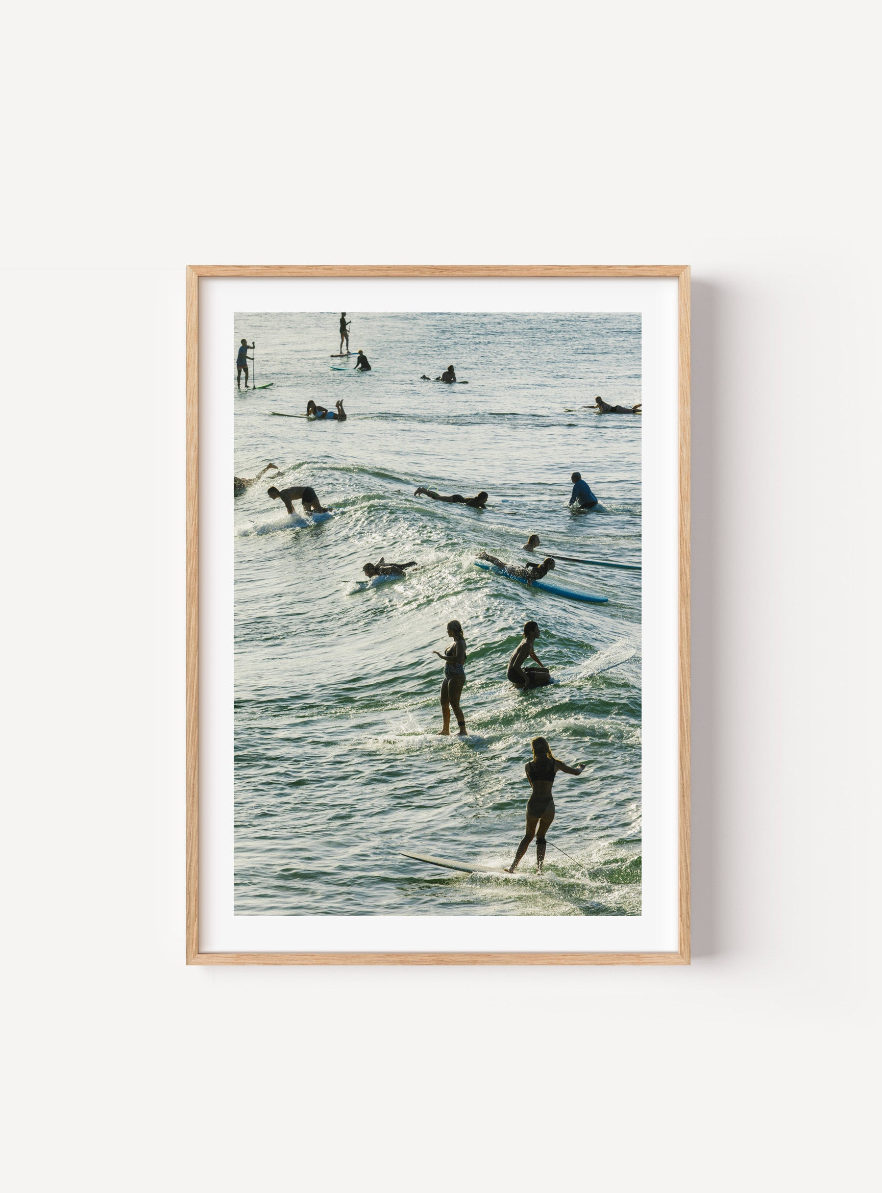 Surfers riding and paddling through layered waves in afternoon light at Yamba, Australia, mocked up in frame