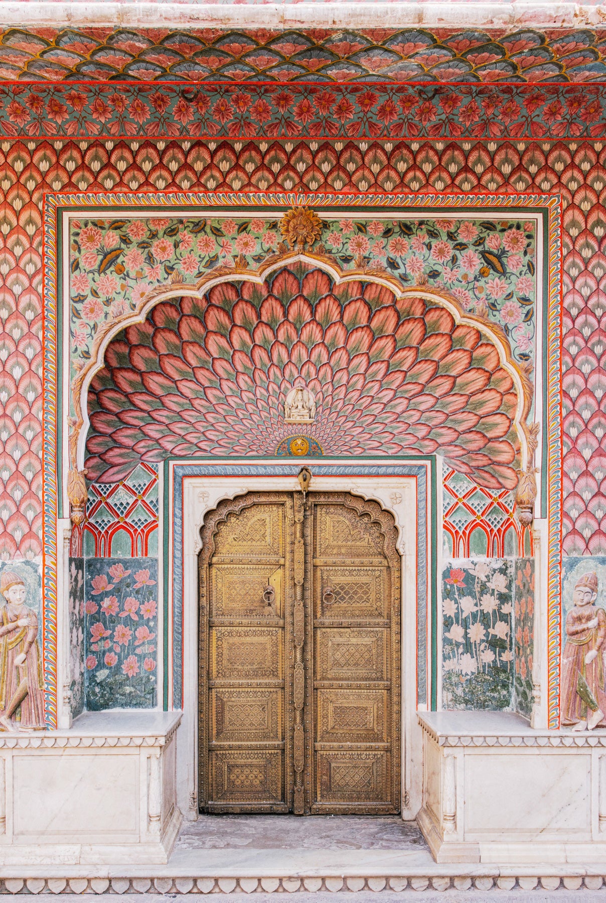 Ornate golden door framed by painted floral arches at Jaipur City Palace, photographed by Elise Hassey