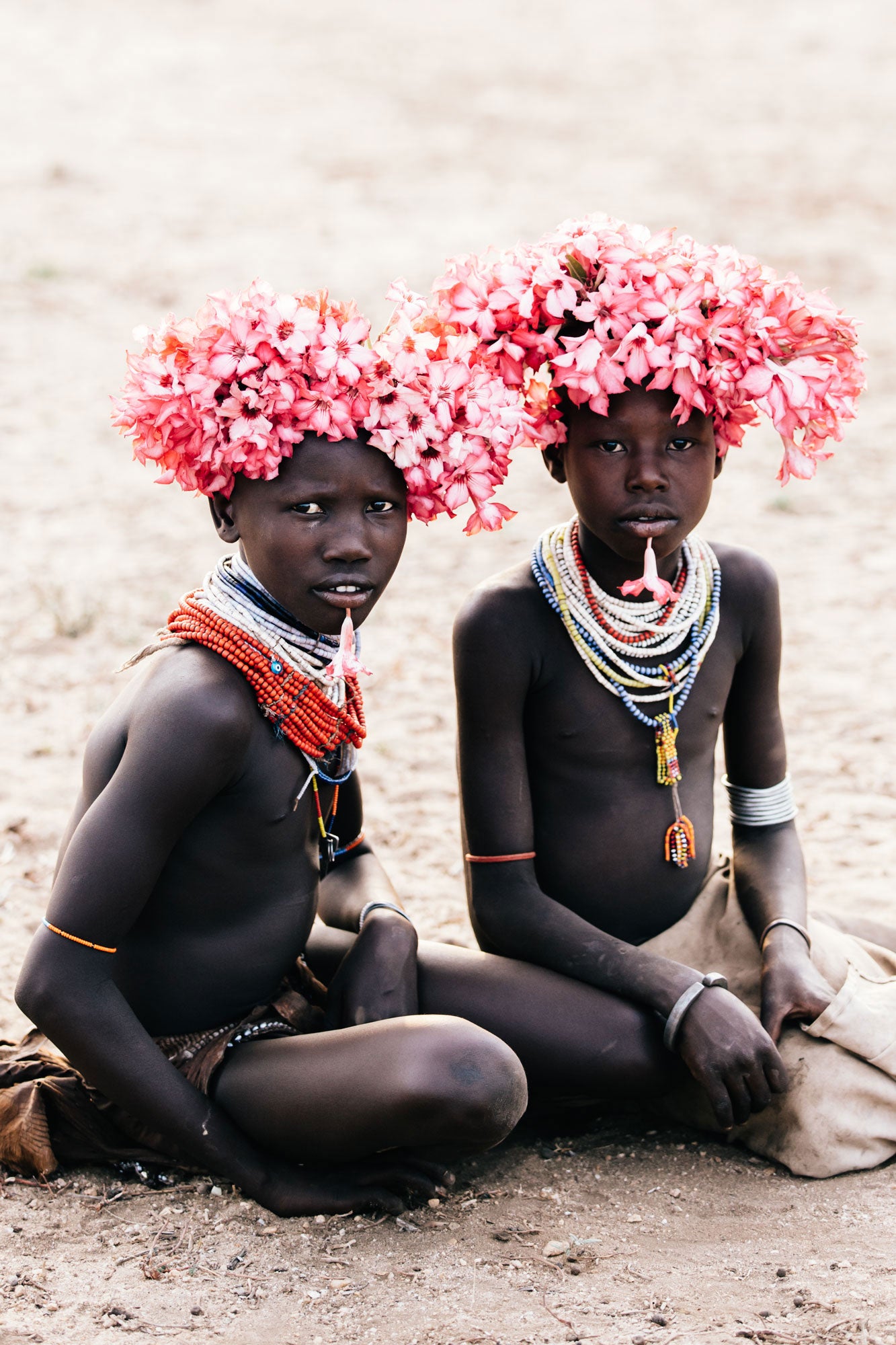 Portrait of two Karo youth in Ethiopia wearing flower crowns and layered necklaces, photographed by Elise Hassey.