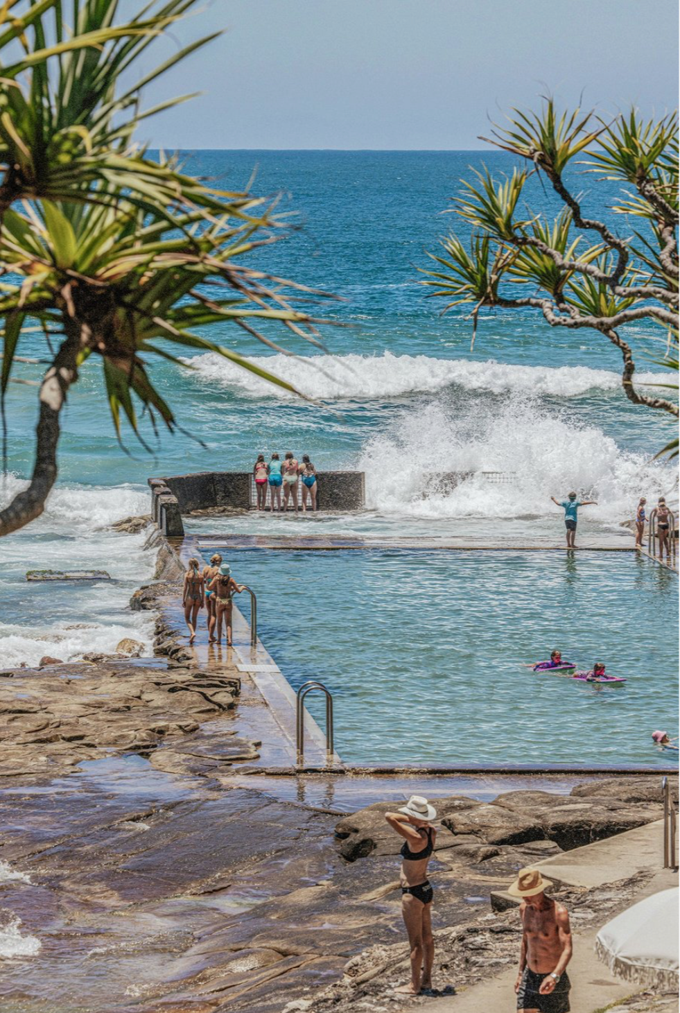 Children standing at the edge of Yamba's ocean pool with waves crashing behind them